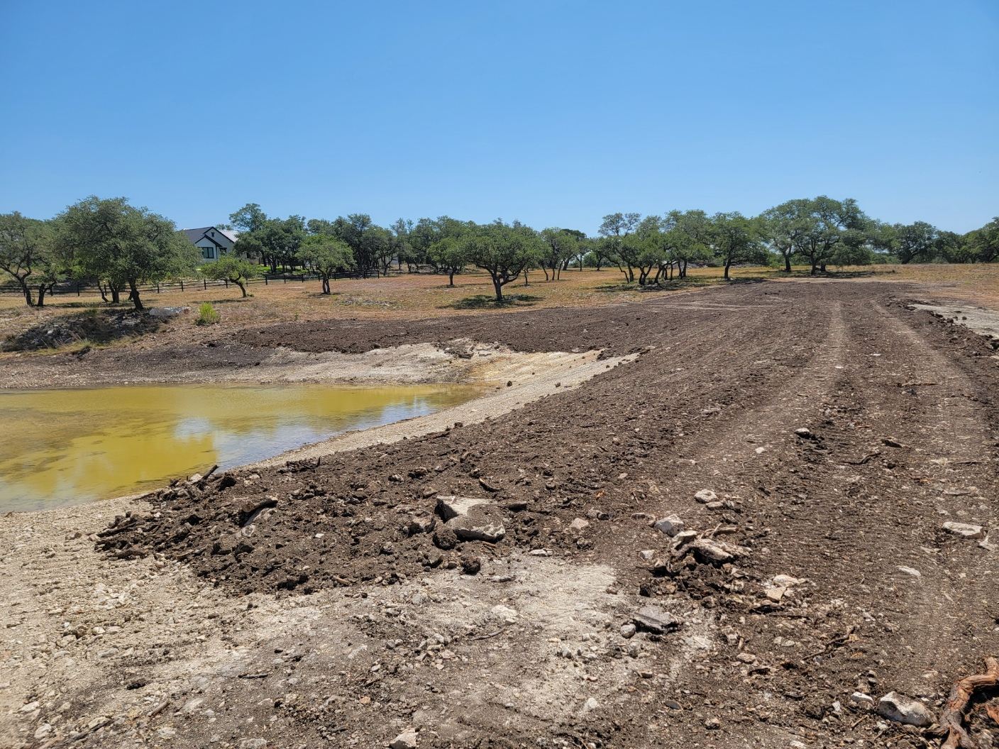 Freshly graded stock tank dam and building site