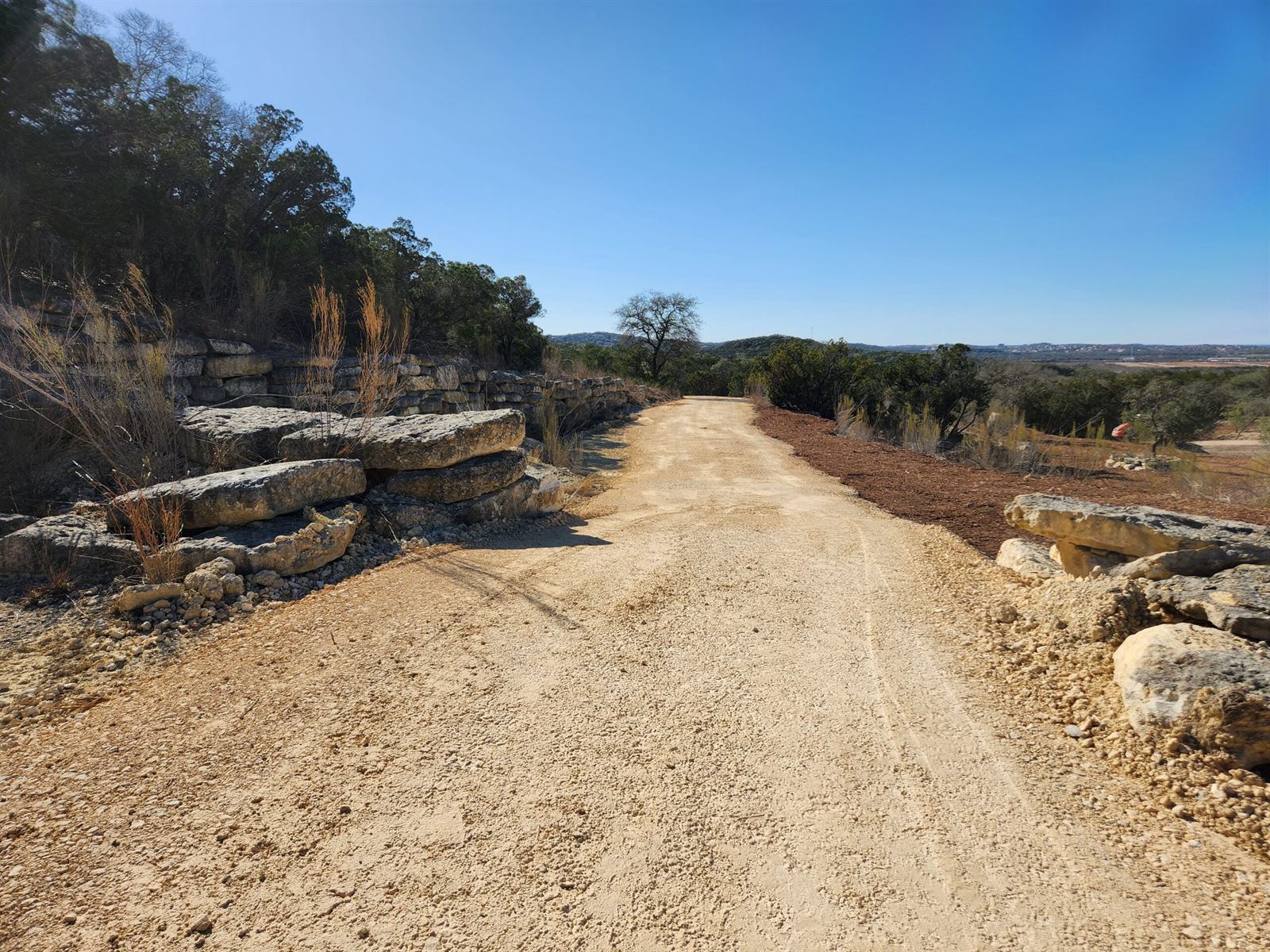 Finished caliche ranch road lined with limestone boulders