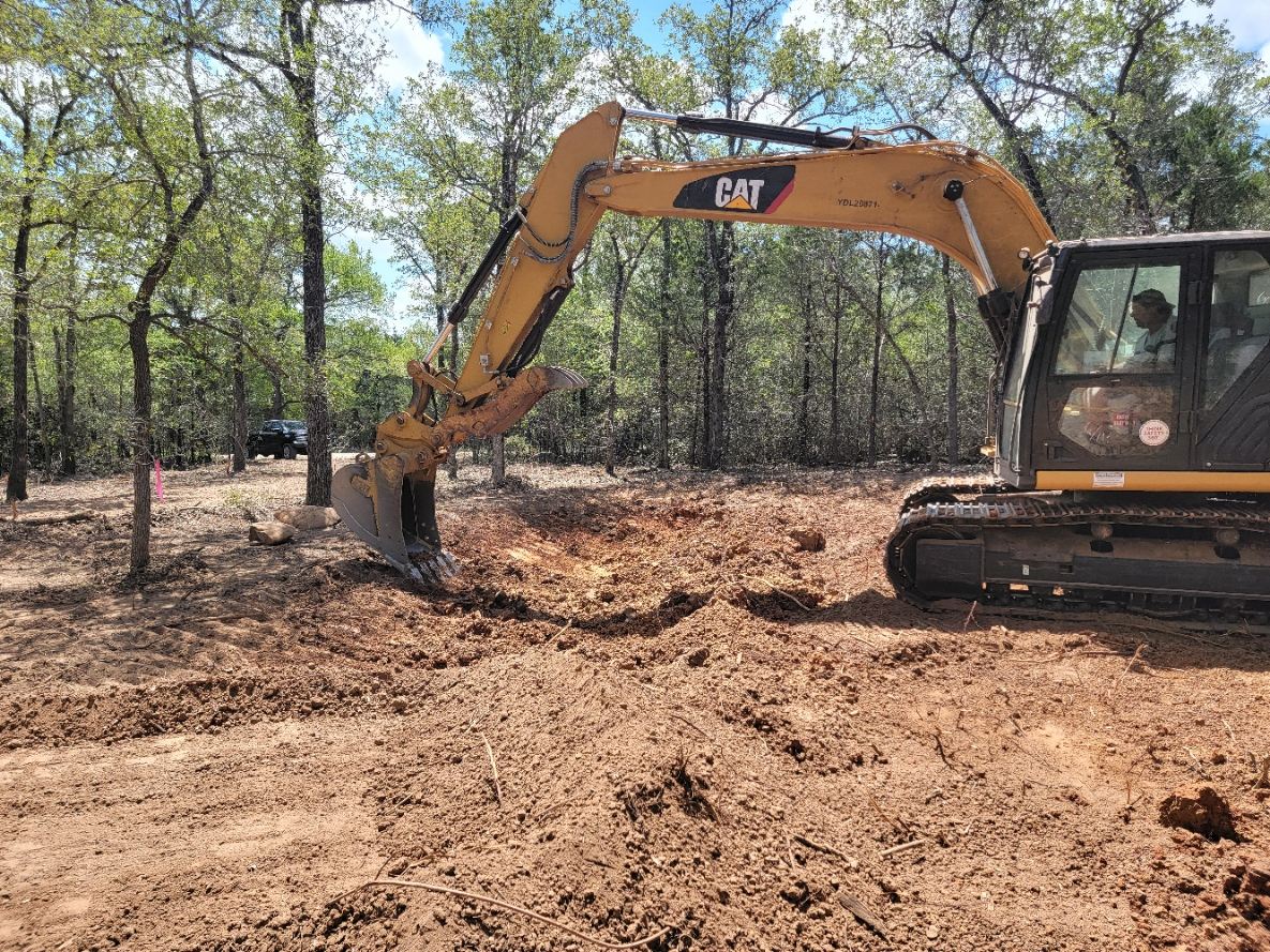 CAT excavator digging on a wooded homesite